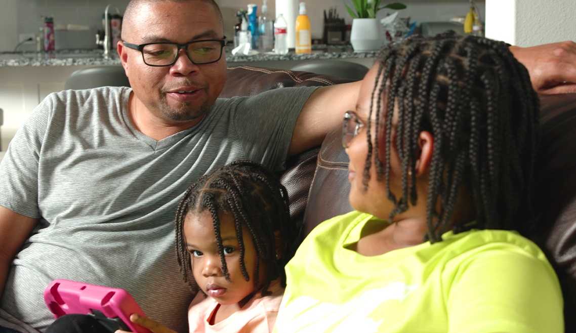 dad sitting on couch with two young daughters