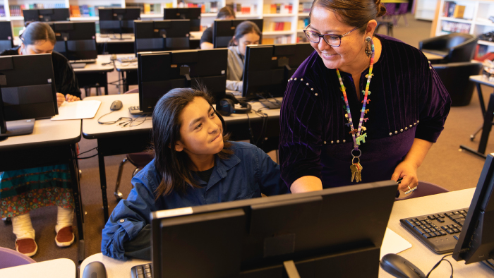 teacher standing with student sitting at computer